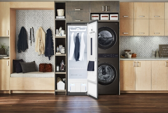 LG steam styler in a modern laundry with two white shirts and a blazer hanging up inside.